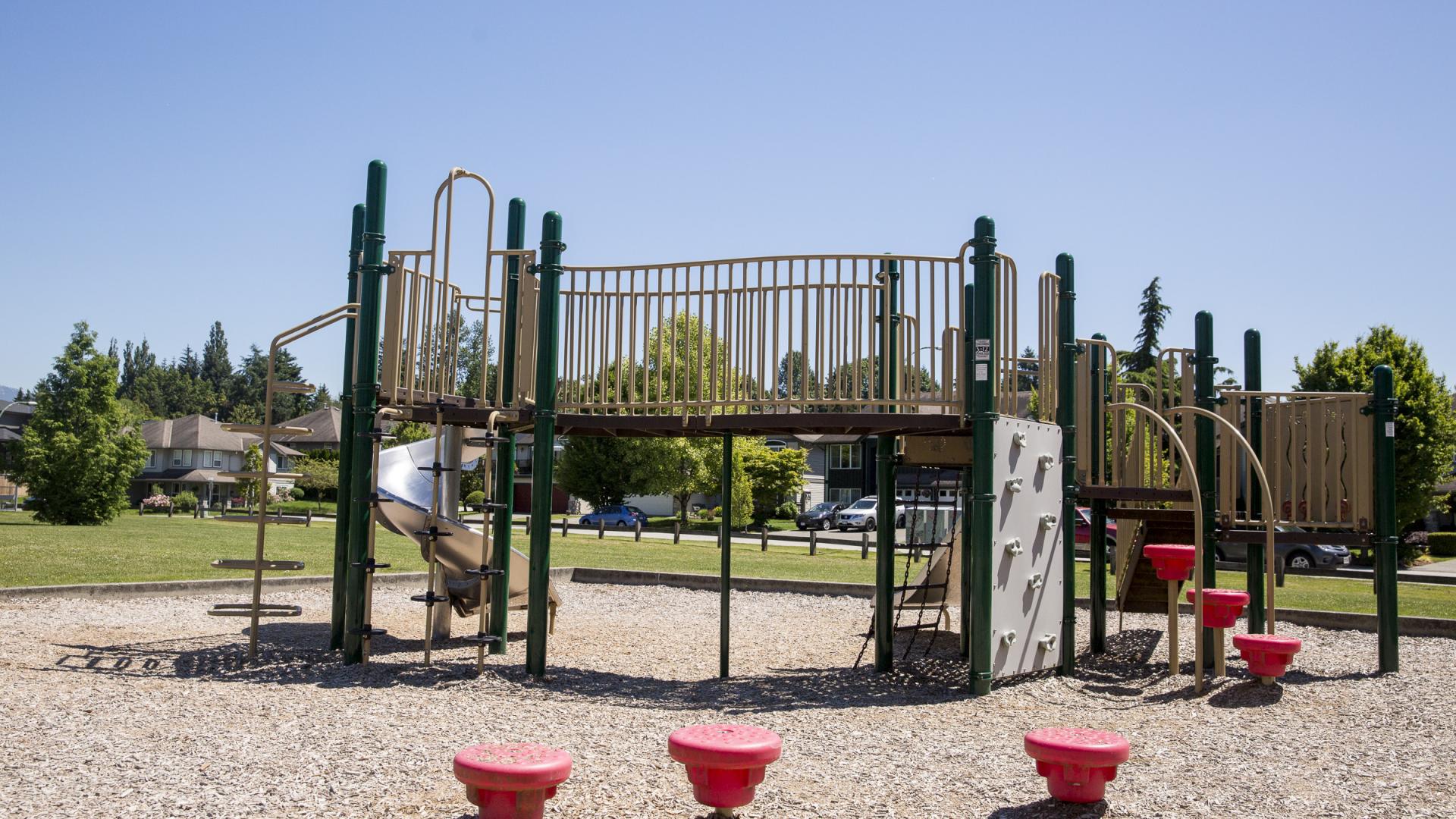A green playground with red elements in Boundary park on a bright sunny day.